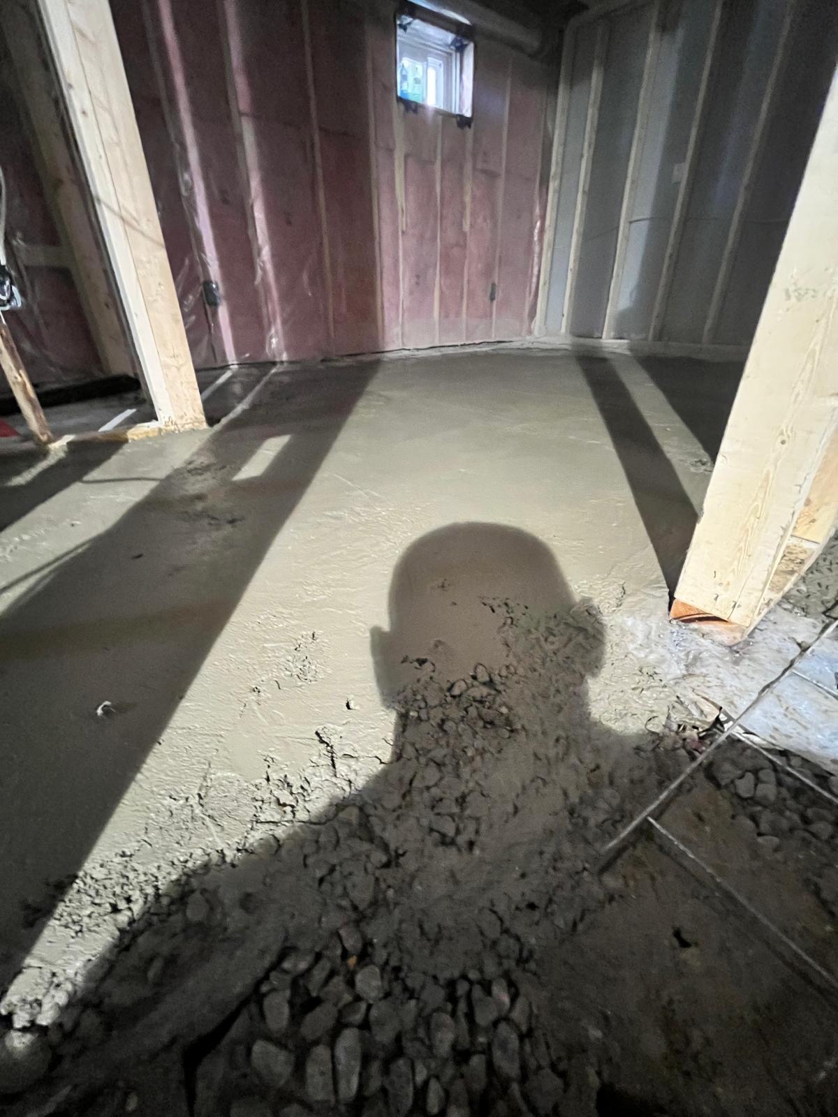 Basement floor levelling in progress, self-levelling cement spreading between framed walls