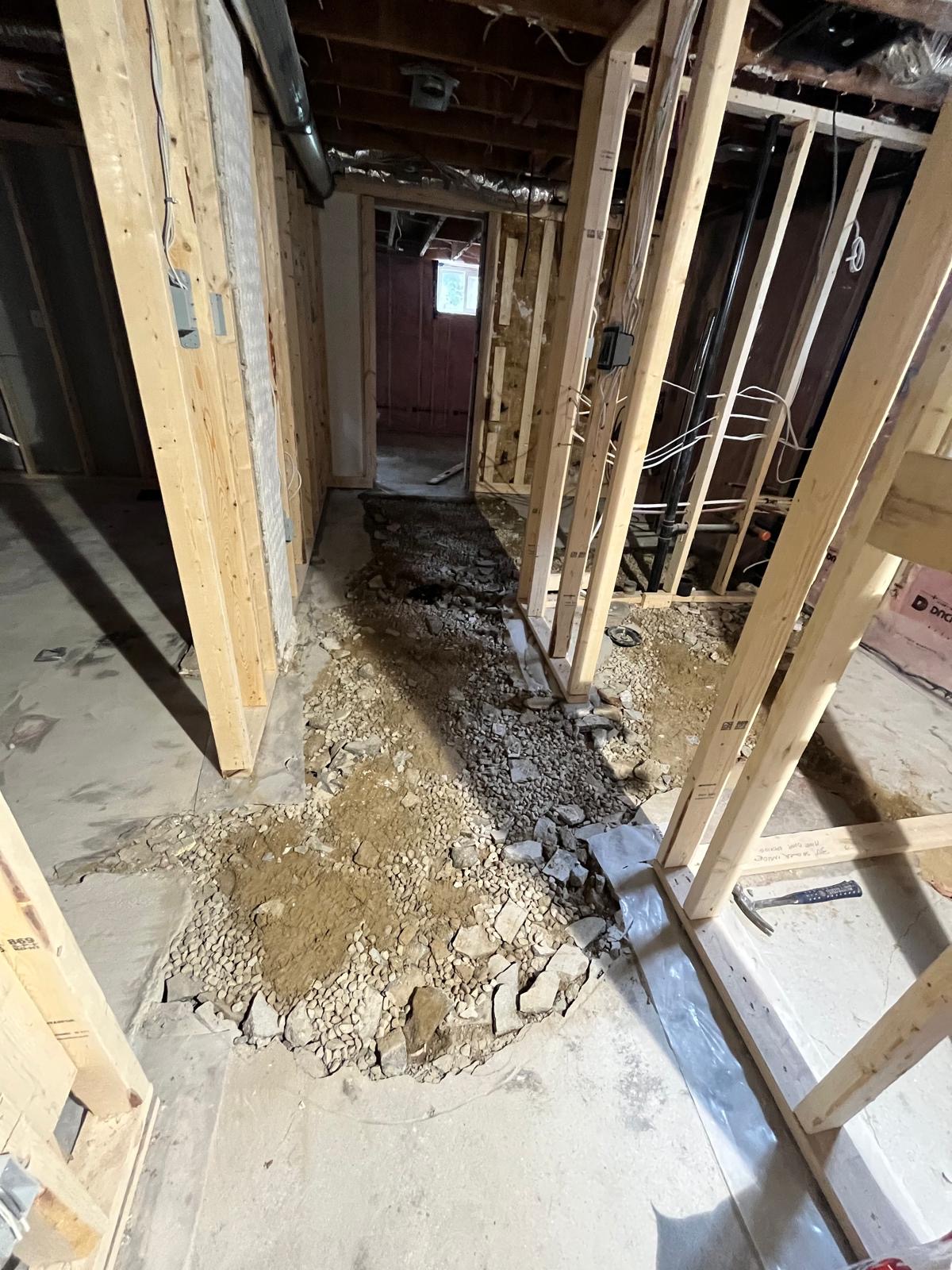 Basement subfloor prep with excavated gravel trench and wood framing before concrete levelling