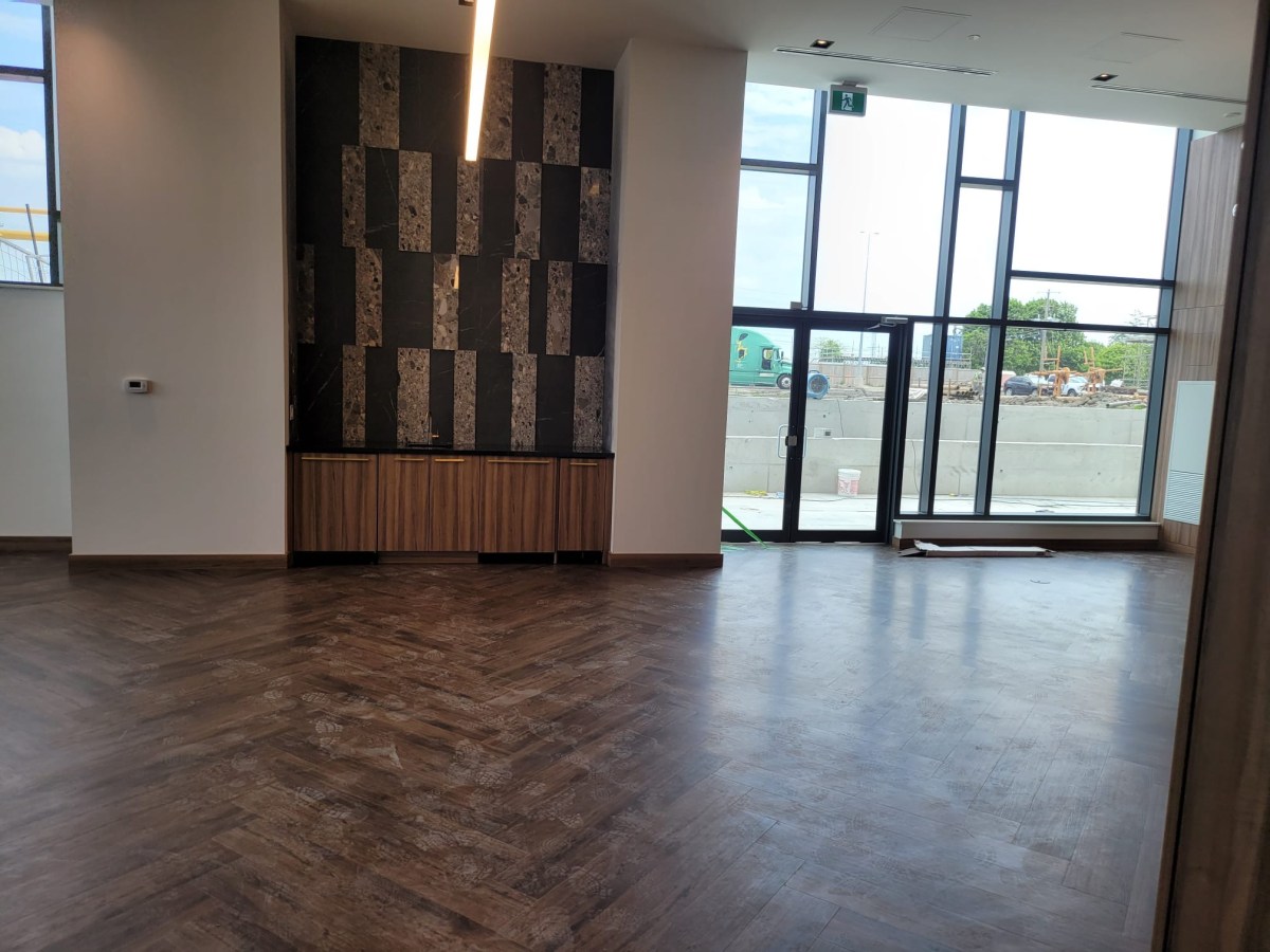 Finished herringbone flooring in a bright Toronto commercial showroom with glass entrance doors