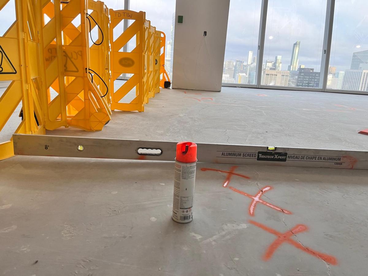 Aluminum screed and spray marks on a concrete slab in a Toronto high-rise before floor levelling