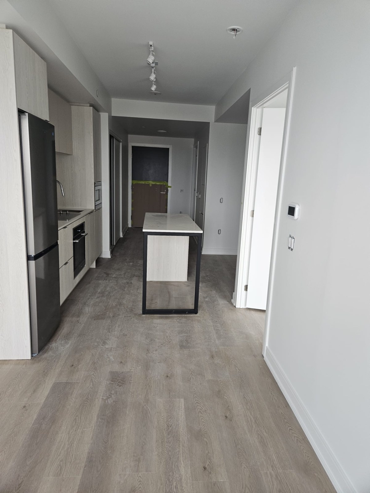 Finished light grey vinyl plank flooring in a Toronto condo kitchen and hallway after floor levelling