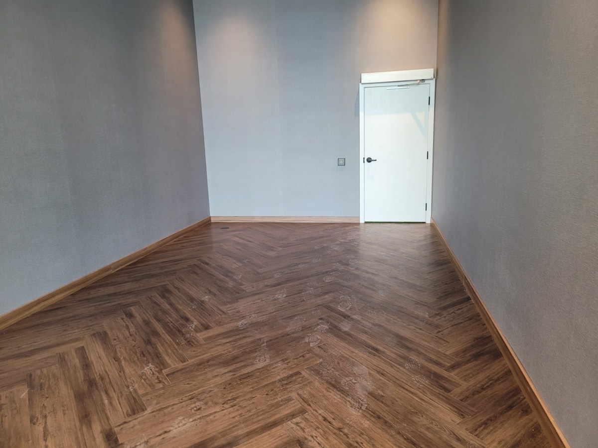 Finished herringbone luxury vinyl flooring in a small Toronto office room with grey walls