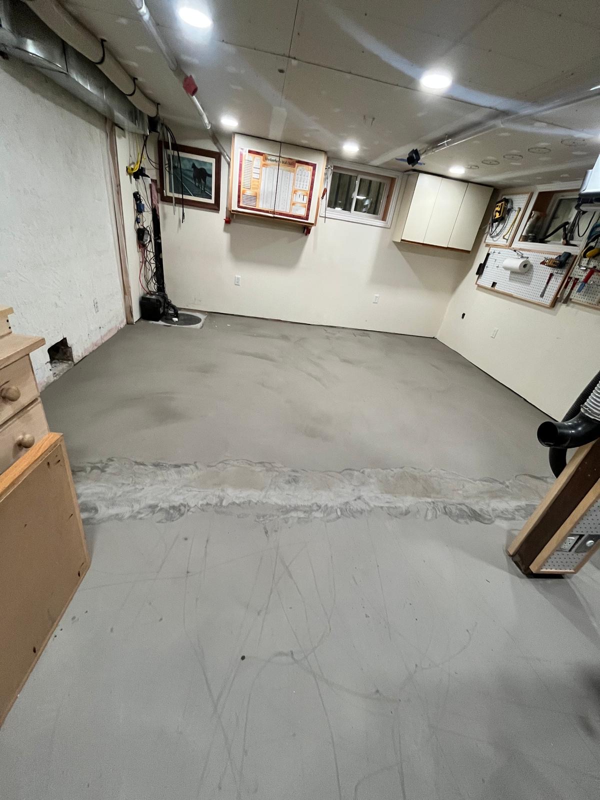 Cured grey self-levelling cement across a home workshop floor ready for finished flooring